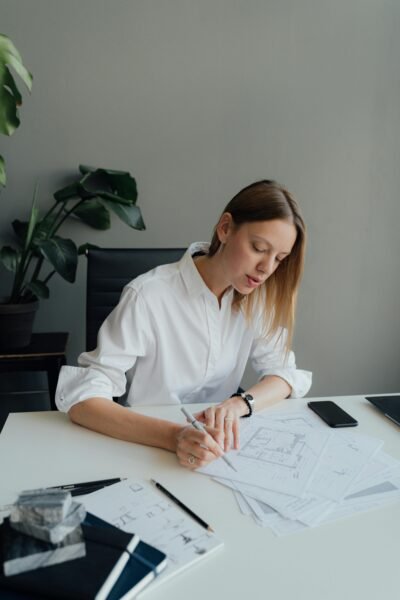 Professional woman architect sketching floor plans while working from home office.